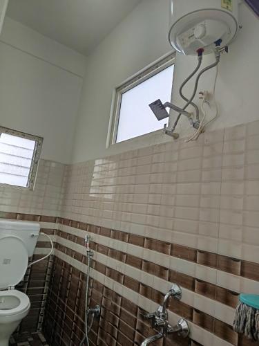 a bathroom with a toilet and a window at Cloud Hill Homestay in Jālāpahār