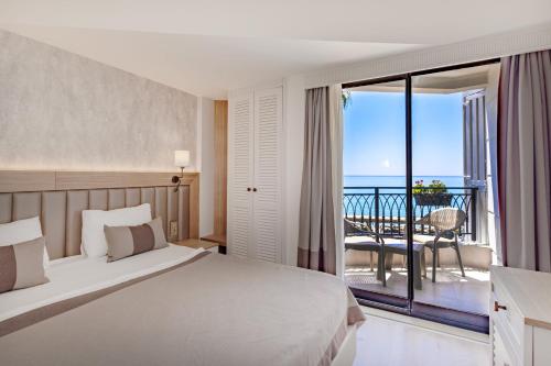 a bedroom with a bed and a balcony with the ocean at DeMANOR HOTEL ADULT ONLY in Alanya