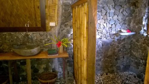 a bathroom with a sink and a stone wall at Friendly Beach in Tanna Island