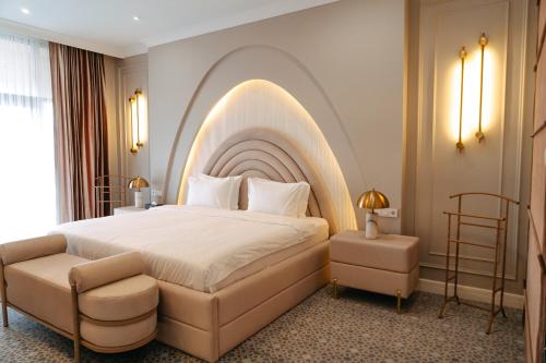 a bedroom with a large bed with an arched headboard at Medina Palace Hotel in Türkistan