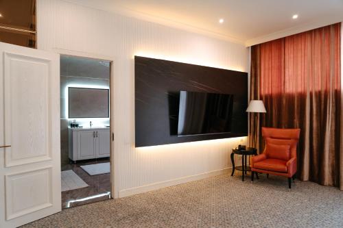 a room with a red chair and a television on a wall at Medina Palace Hotel in Türkistan
