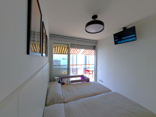 a bedroom with a bed and a large window at Coblanca 41-spectacular views-gym-heated pool-sauna-jacuzzi-wifi-3 minutes walk from the sear in Benidorm