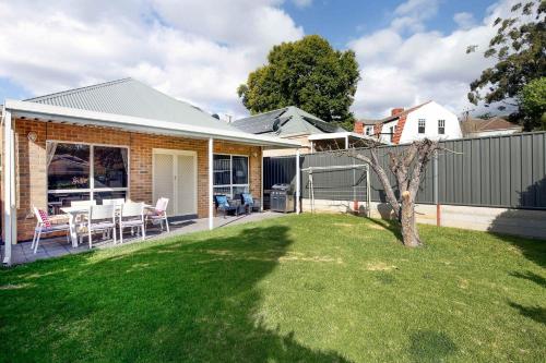 a house with a yard with a fence at Archie's Townhouse 4BD 2BT in Glenunga
