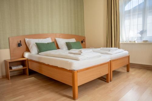 a large bed with white sheets and green pillows at Levendula Resort és Rendezvényközpont in Bogács