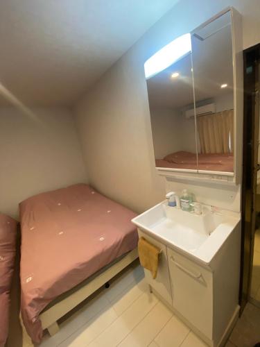 a small bathroom with a bed and a sink at Hotel MR TOMO ATAMI 301 in Atami