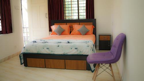 a bedroom with a bed and a purple chair at Haven Grace in Kovalam