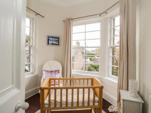 a baby crib in a room with windows at Rowan Tree House in Brechin