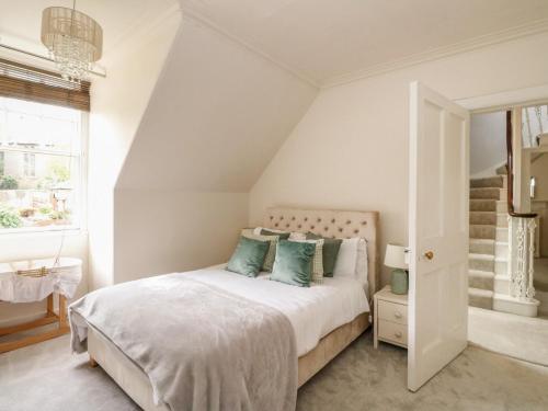 a white bedroom with a bed with blue pillows at Rowan Tree House in Brechin