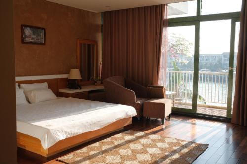 a bedroom with a bed and a chair and a window at Lam Home Tuần Châu in Ha Long