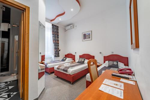 a hotel room with two beds and a table at Hotel Varazdin in Varaždin