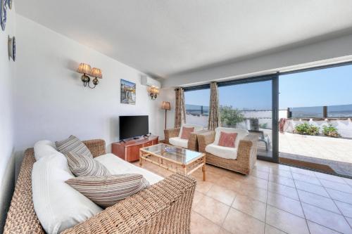 a living room with a couch and chairs and a tv at Bungalow Olas del Risco - Ocean views - Beach 2 min By Lanzarote Vacation Homes in Famara