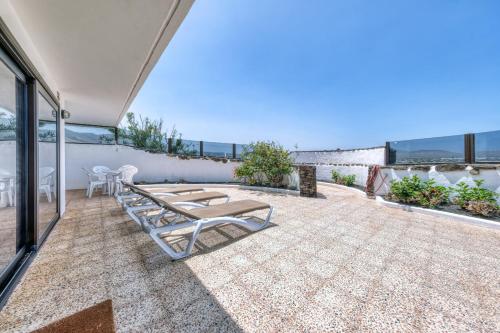 a patio with chairs and tables on top of a building at Bungalow Olas del Risco - Ocean views - Beach 2 min By Lanzarote Vacation Homes in Famara