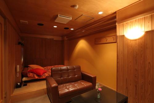 a bedroom with a couch and a bed in a room at Hotel Water Gate Tajimi in Tajimi