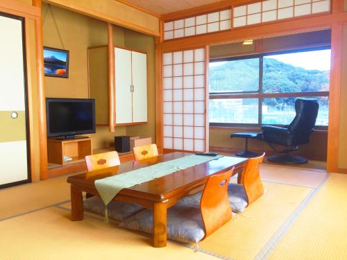 a living room with a wooden table and a chair at Hoshi Meguri in Shimoda