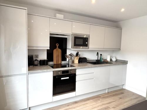 a kitchen with white cabinets and a stove and a microwave at Smithy Mills in Halifax