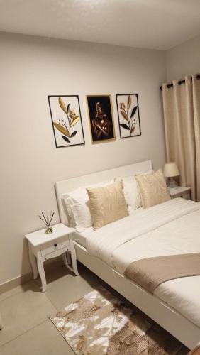 a white bedroom with a bed and a table at Minnestayairbnb in Gaborone