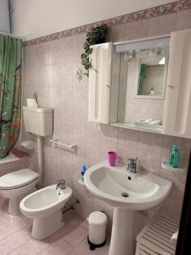 a bathroom with a sink and a toilet and a mirror at La Puteca di Nonna Cia in Andrano
