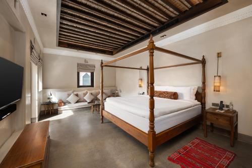 a bedroom with a canopy bed and a couch at The Chedi Al Bait, Sharjah in Sharjah