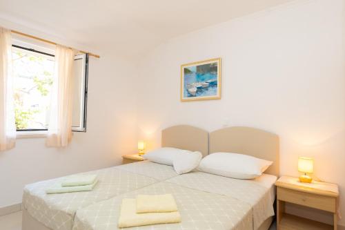a white bedroom with a bed with two towels on it at Apartments Baltazar with Sea View&Jacuzzi in Dubrovnik