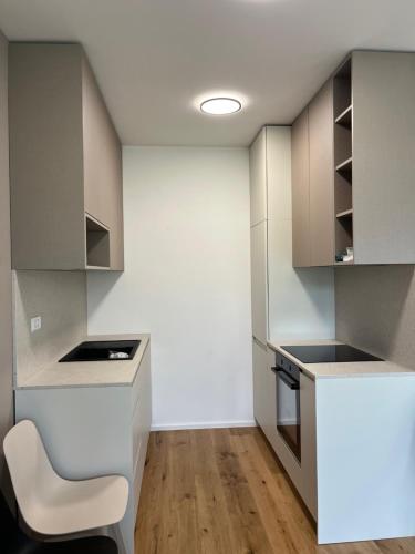 a kitchen with white cabinets and a white chair at TB7 Sg in Slovenj Gradec