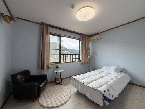 a bedroom with a bed and a chair and a window at Senbonzakura Yoshino in Yoshino
