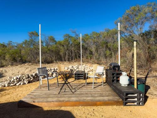 a wooden deck with a table and chairs on the beach at Hill River Nature Reserve by Tiny Away in Jurien Bay