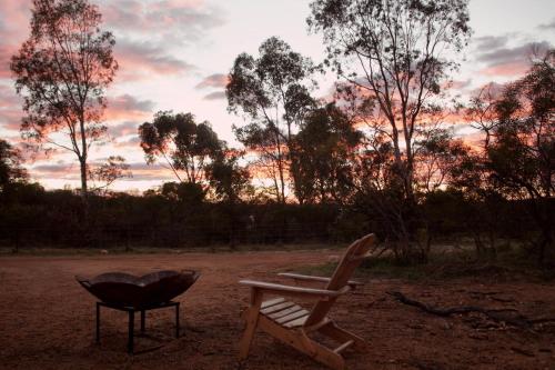 a grill and a chair in a field with a sunset at Hill River Nature Reserve by Tiny Away in Jurien Bay
