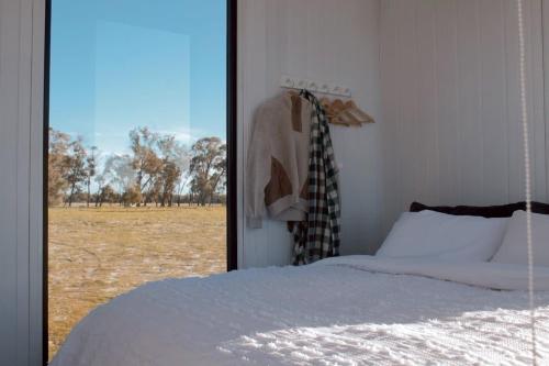 a bedroom with a bed and a view of a field at Orana Cabin by Tiny Away in Cherry Tree Pool