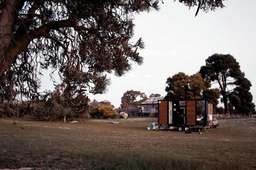 a truck parked in a field next to a tree at Orana Cabin by Tiny Away in Cherry Tree Pool