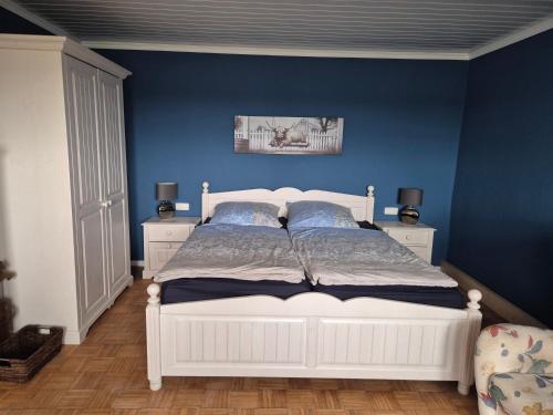 a bedroom with a white bed with blue walls at Entspannen auf der Old Charmi Ranch in Kutenholz