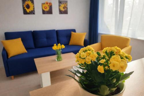 a living room with a blue couch and a table with yellow flowers at Apartament Bałtycka Sardynka in Ustka