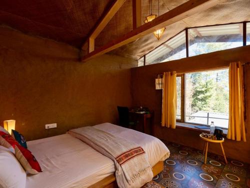 a bedroom with a bed and a large window at Nomad Eco Retreat in Shimla