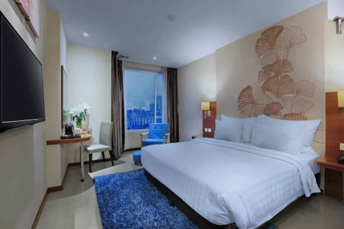 a hotel room with a bed and a television at Aston Inn Gideon Batam in Nagoya
