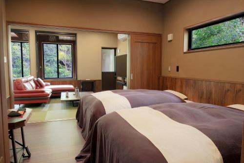 a hotel room with two beds and a couch and windows at Ryokan Kono-Yu in Minamioguni