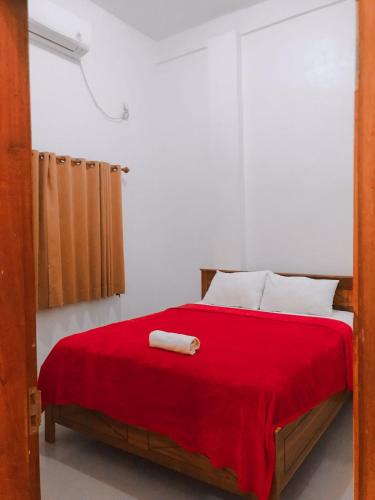a bedroom with a bed with a red blanket at Anorawi surf accommodation in Maluk