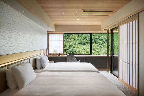 two beds in a room with a large window at Hatsuhana in Hakone