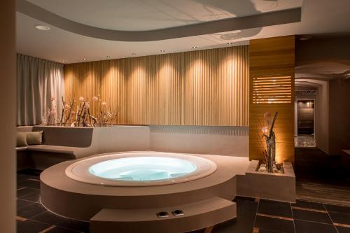 a bathroom with a large tub in the middle of it at HOTEL POST alpine cityflair in Brunico