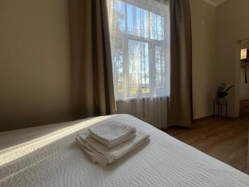a bed with two white towels on it with a window at RUMIDO Station in Valmiera
