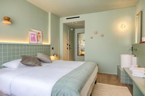 a bedroom with a large white bed and a mirror at Maison Arya in Brussels