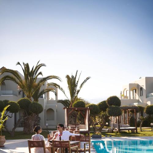 a group of people sitting at a table by a pool at Malena Hotel & Suites - Adults Only by Omilos Hotels in Amoudara Herakliou
