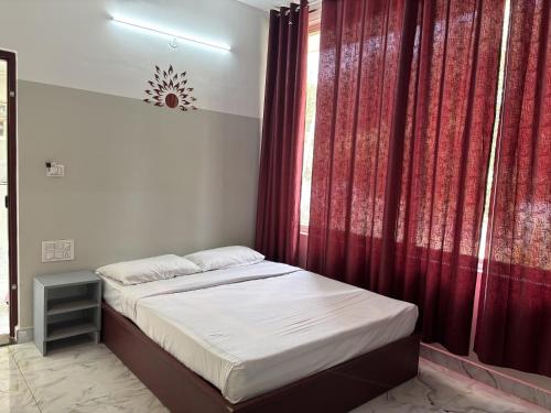a bedroom with a bed with a red curtain at Twinkle Clouds Home Stay in Chikmagalūr