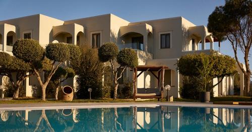 a large white house with a swimming pool in front of it at Malena Hotel & Suites - Adults Only by Omilos Hotels in Amoudara Herakliou