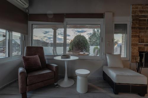 a living room with a chair and a table and a window at SENSEs VILLA SPA in Aghia Marina