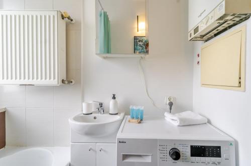 a white bathroom with a sink and a mirror at Mastalerza Spacious Apartment by BookingHost in Gliwice