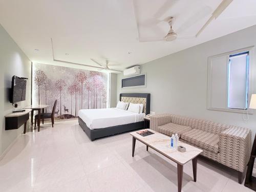 a bedroom with a bed and a couch and a table at Hotel Nova Vista in Rajkot