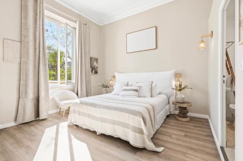 a white bedroom with a bed and a window at Villa Claudia Hotel Cannes Centre - Parking in Cannes