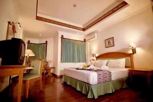 ein Schlafzimmer mit Bett, Schreibtisch und Fernseher in der Unterkunft Kresna Hotel in Wonosobo