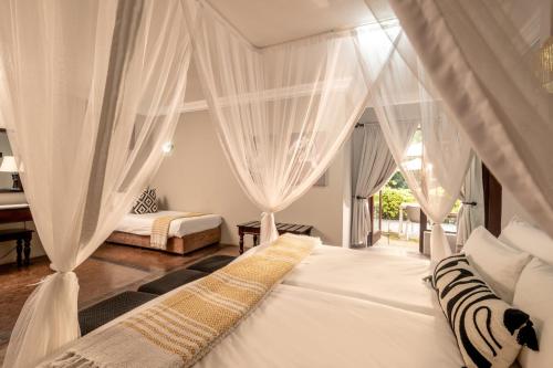 a bedroom with two beds with white drapes at Stille Woning Guesthouse in White River