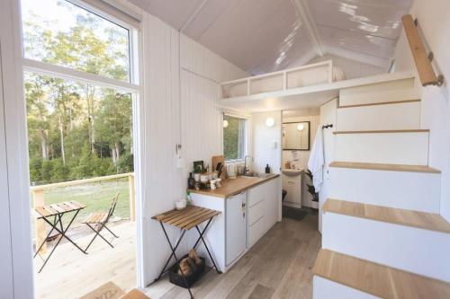 a tiny house with a kitchen and a large window at Kookaburra Tiny House by Tiny Away in Palmwoods