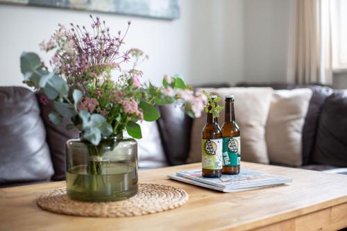 two bottles of beer on a wooden table with flowers at Backhaus Ost in Bisdorf